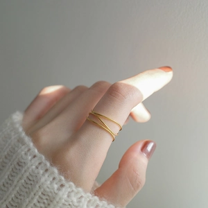 Detalle de un anillo minimalista multicapa en oro usado en el dedo índice