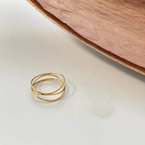 Vista detallada de anillos minimalistas dorados con capas sobre superficie de madera