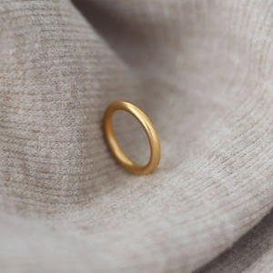 Anillo minimalista de acero de titanio oro mate 18k sobre fondo de tejido beige