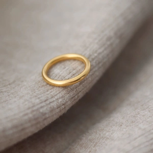 Anillo minimalista de acero de titanio dorado de 18k sobre fondo de tela suave texturizada