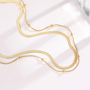 Detail of gold double-layer necklace featuring snake chain and delicate bead chain