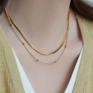 Double-layered gold titanium steel necklace featuring a snake chain and delicate bead accents