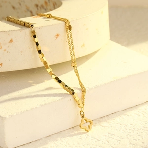 Elegante goldene Doppelschicht Kleeblatt Fußkette aus Titanstahl auf weißem Stein