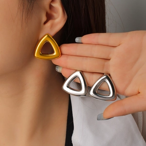 Dettaglio macro di orecchini a lobo geometrici a triangolo in oro e argento per donna