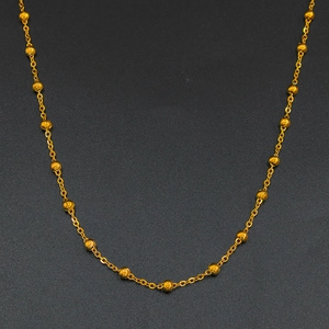 Collana minimalista in acciaio inossidabile dorato con perline lucide su sfondo nero