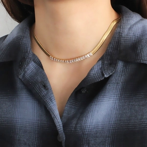 Collier maille serpent dorée avec zircons baguettes porté par un mannequin sur bleu