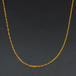 Dettaglio macro di una sottile catenina d'oro con maglia a onde e lucentezza metallica