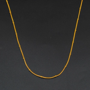 Dettaglio macro della collana a catena a serpente dorata con piccole perline cilindriche oro