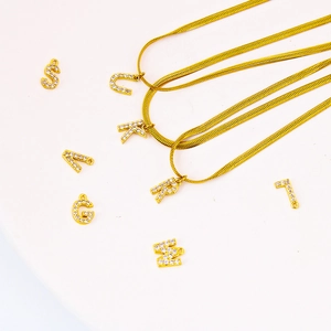 Collana a catena serpente dorata con ciondoli a lettera ricoperti di zirconi brillanti