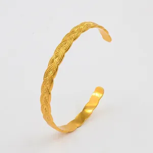 Detailed view of golden C-shaped cuff bracelet with braided texture and wavy edges