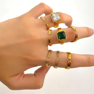 Détail de bagues dorées avec zircon carré vert et anneaux à texture vintage empilables