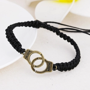 Detail of hand-woven black rope bracelet with bronze handcuffs and Freedom engraving
