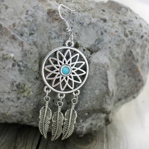 Detalle de los pendientes atrapasueños bohemios con cuentas turquesas y colgantes de pluma