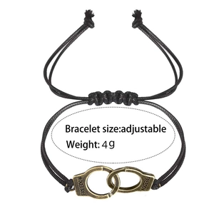 Detail of adjustable black woven bracelet with brass handcuffs engraved with Freedom