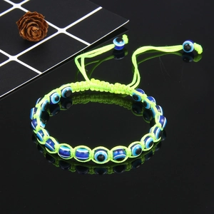 Detailed macro view of adjustable fluo-green braided bracelet with blue evil eye beads