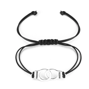 Detail of black woven rope bracelet with silver handcuffs charm and Freedom engraving