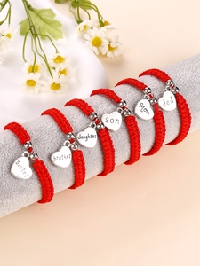 Close-up of handmade red braided bracelets with engraved heart family charms