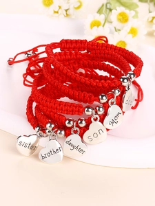 Detail of red woven bracelets with heart charms for family members and silver beads