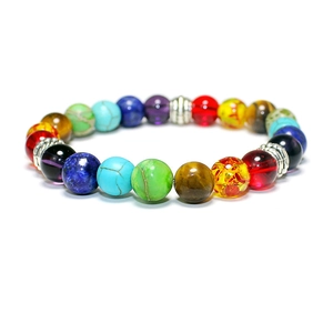 Macro detail of seven chakra beaded bracelet with metallic spacers on white background