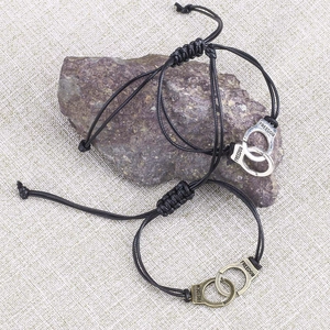 Detail of adjustable woven handcuff bracelets with Freedom engraving on linen background