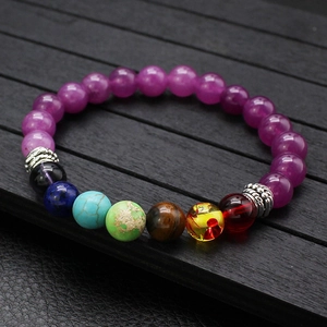 Detail eines Perlenarmbands mit lila Achat und bunten Heilsteinen auf Holzoberfläche