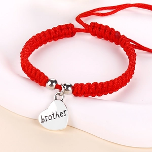 Macro detail of red woven rope bracelet featuring a heart pendant with brother engraving