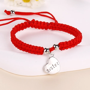 Close-up of handmade red braided cord bracelet with silver heart sister pendant charm