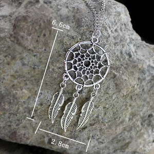 Collar atrapasueños con plumas dimensiones 6,6cm x 2,8cm sobre fondo de piedra rústica