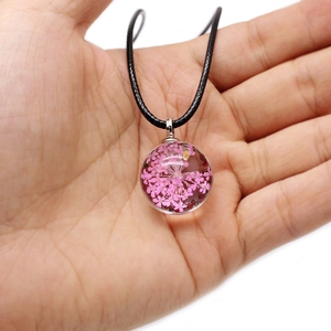 Handmade necklace with round glass pendant featuring real pink dried flowers and black cord