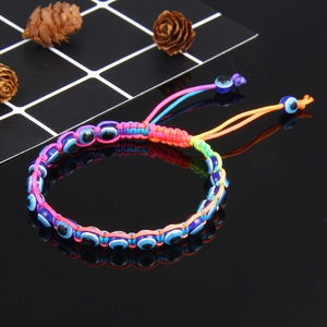 Colorful handmade braided Evil Eye bracelet with adjustable cord on reflective black surface