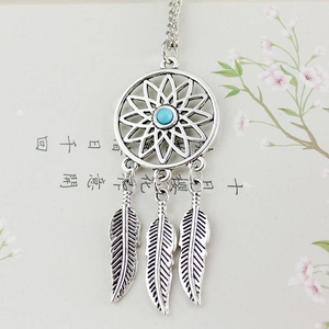 Detalle del collar atrapasueños con cuenta turquesa y colgantes de plumas metálicas