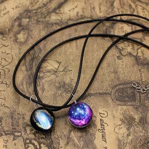 Close-up of galaxy glass sphere pendants with vibrant nebulae on vintage map background