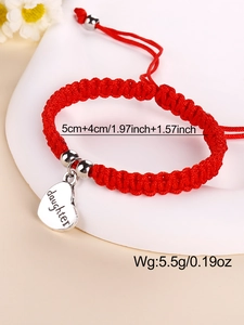 Close-up of red woven bracelet featuring a silver heart charm engraved with daughter