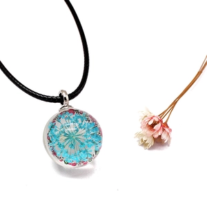 Detailed macro view of a spherical glass pendant with real blue dried flowers inside