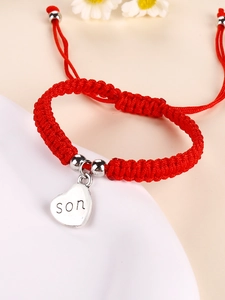 Detail of red handmade braided bracelet with heart charm engraved with the word son