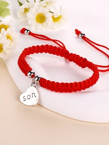 Detailed macro view of red braided bracelet featuring a heart charm engraved with son