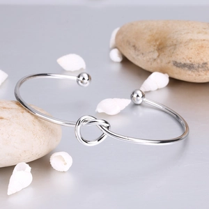 Macro detail of silver knot cuff bracelet with polished finish and spherical ends