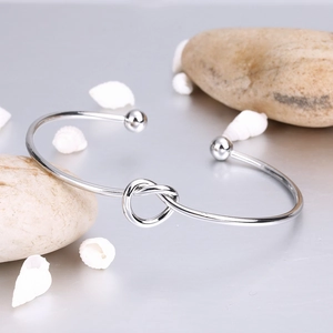 Close-up of silver knotted open cuff bracelet with spherical ends on natural stones