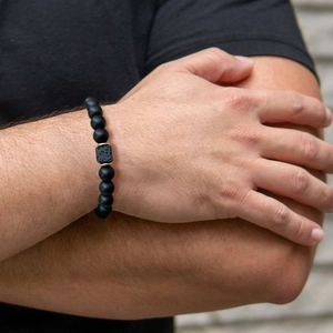 Detail of matte black agate beaded bracelet with porous lava stone and gold accents on wrist