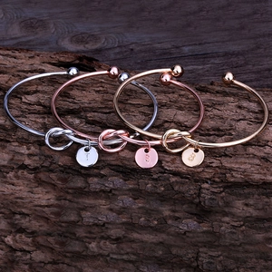 Détail des bracelets à nœuds en or, or rose et argent avec pendentifs de lettres