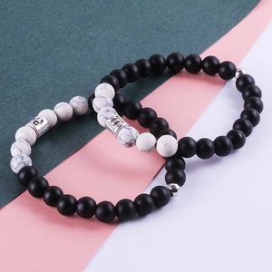 Vue détaillée de bracelets en perles de pierre marbre noir mat et blanc avec breloques argent