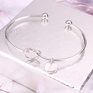Détail du bracelet jonc nœud en argent avec pendentif lettre A sur un coffret