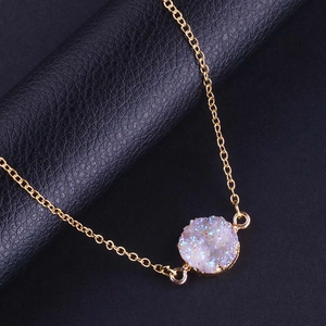 Détail du pendentif rond en cristal druzy coloré avec chaîne dorée sur cuir noir