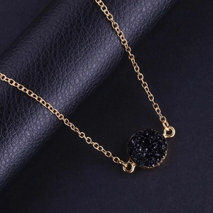 Vue détaillée d'un pendentif en cristal druzy noir sur une fine chaîne dorée élégante