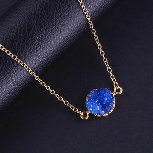 Détail du pendentif druzy bleu avec placage en or sur fond de cuir noir texturé