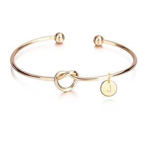 Détail macro du bracelet à nœud en or rose avec un pendentif gravé de la lettre J