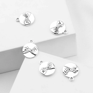 Dettaglio di cinque ciondoli rotondi in argento con incisione Pinky Swear e anelli pendenti