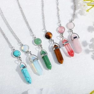 Close-up of hexagonal crystal pillar necklaces in turquoise, tiger eye, and rose quartz