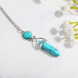 Detail of bohemian turquoise hexagonal bullet pendant necklace with silver metal setting