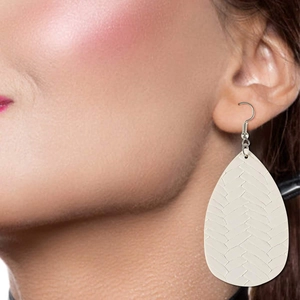 Primo piano di orecchini a goccia color crema con trama intrecciata su una modella